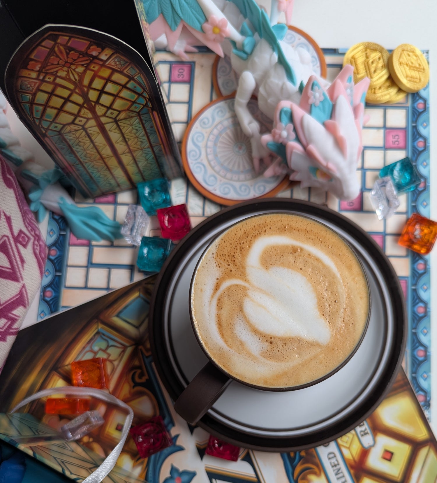 Cappuccino with latte art on a boardgame with 3d printed dragon and dice.