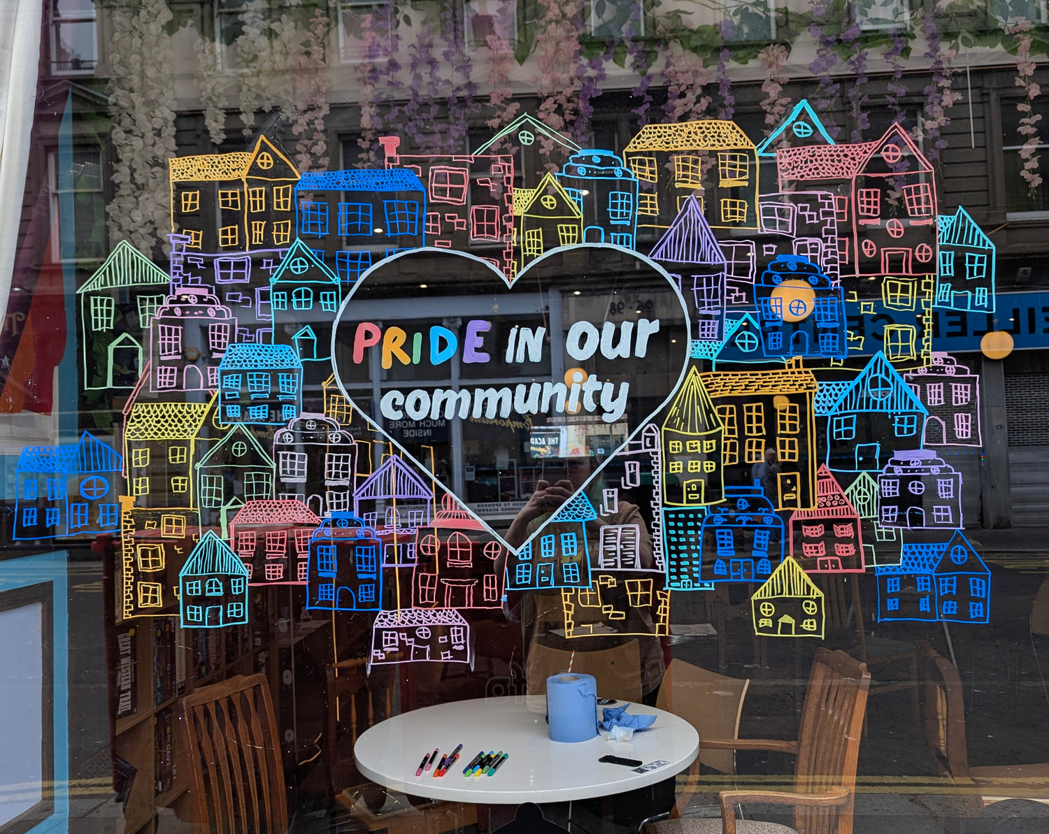 Hand drawn image with 'Pride in our community' text and colourful houses in a window display.