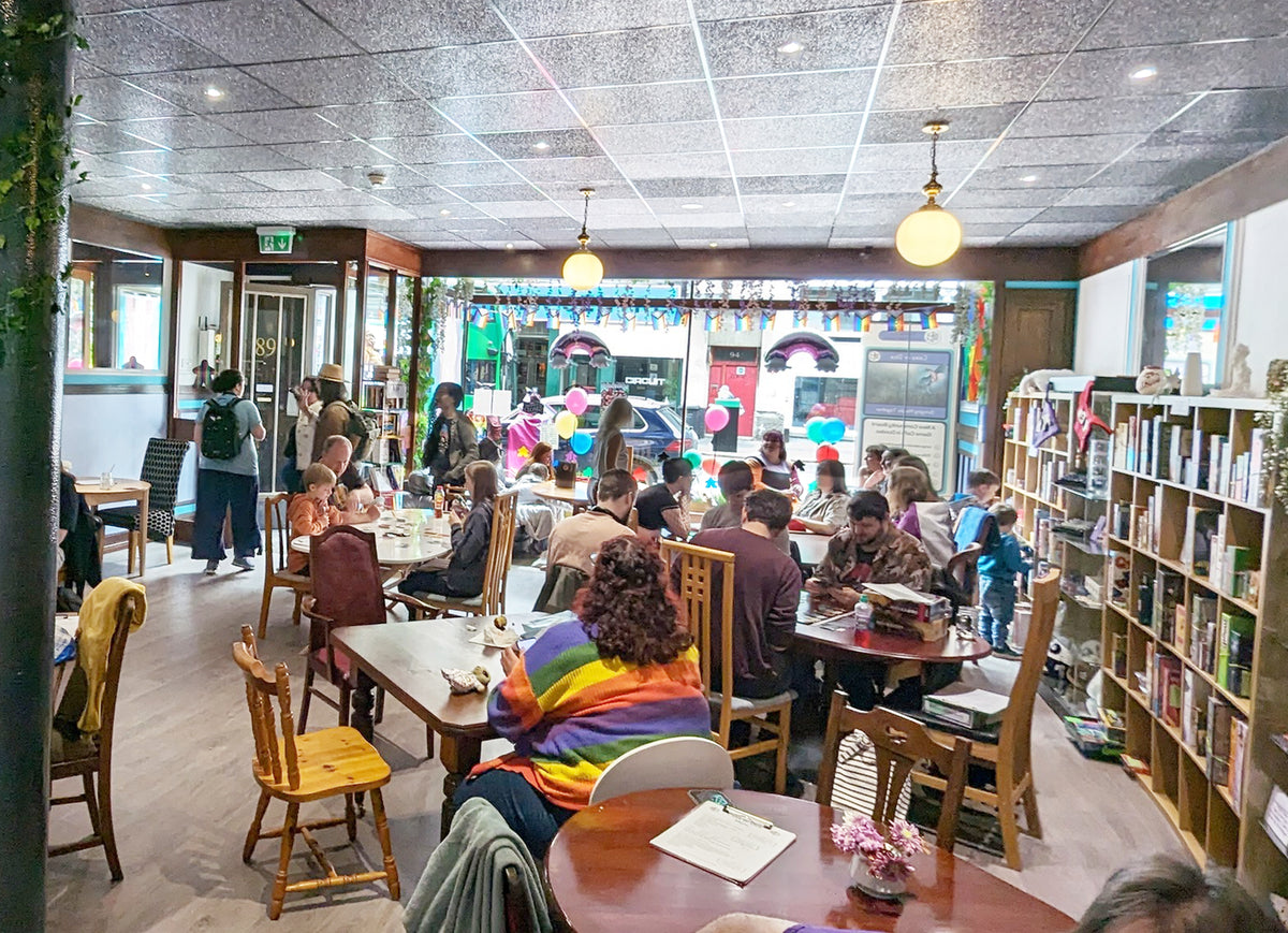 People sitting at tables in our café with shelves of board games
