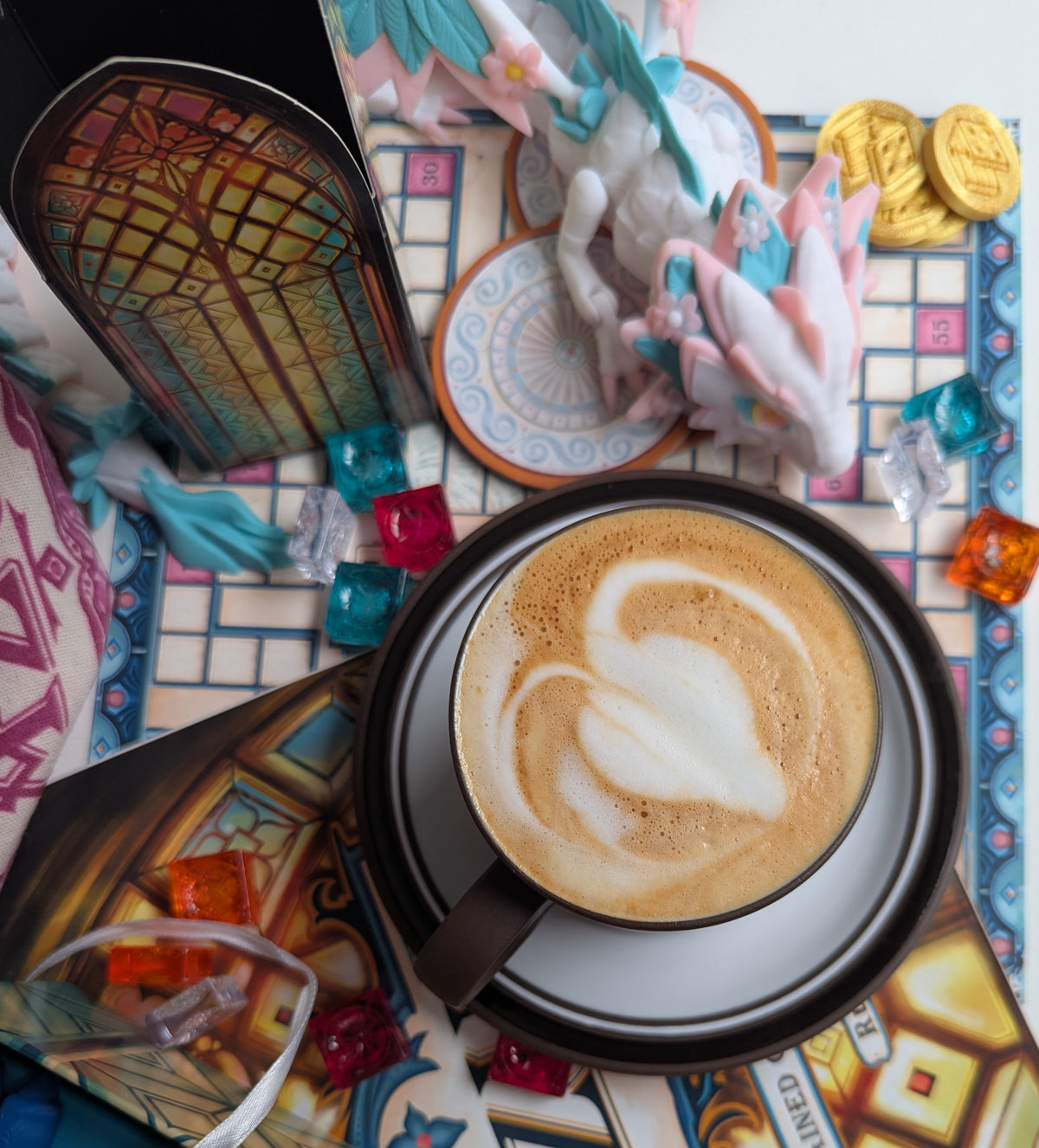 Cappuccino with latte art next to a 3D printed dragon and dice